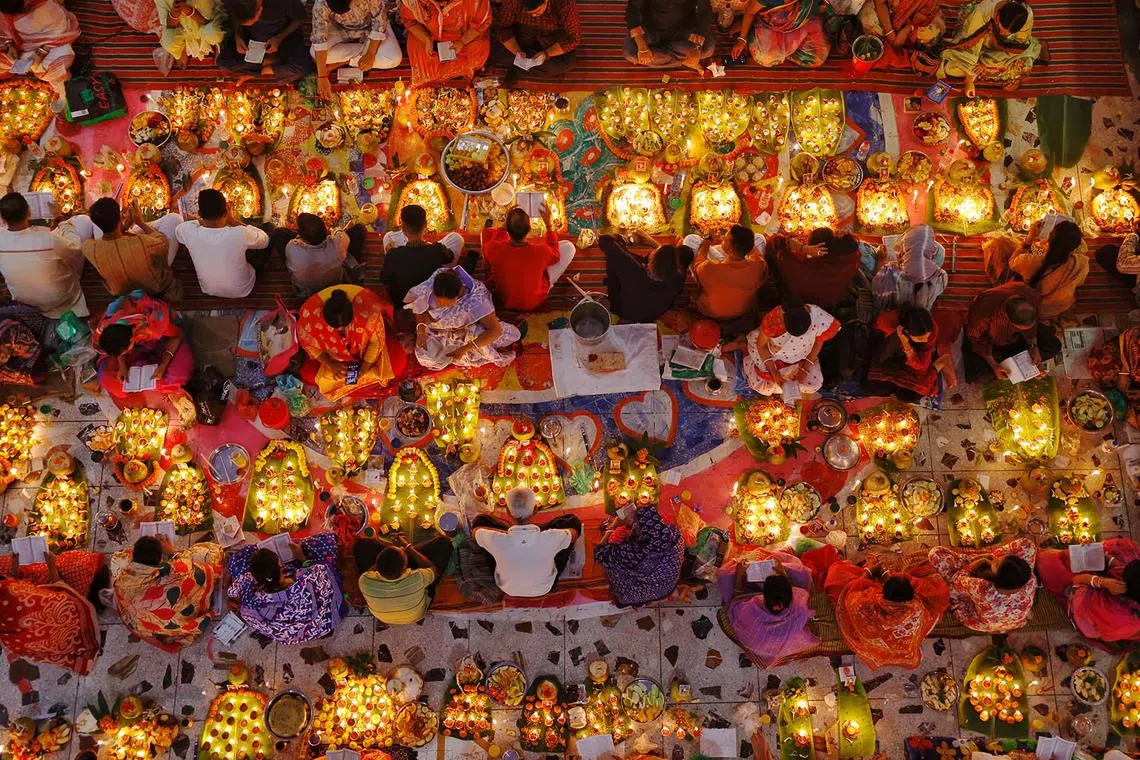 Hindu devotees sitting together in front of oil lamps and candles, and praying to Lokenath Brahmachari, a Hindu saint and philosopher, as they observe the Rakher Upobash festival, at a temple in Dhaka, Bangladesh, Nov 12, 2024. 