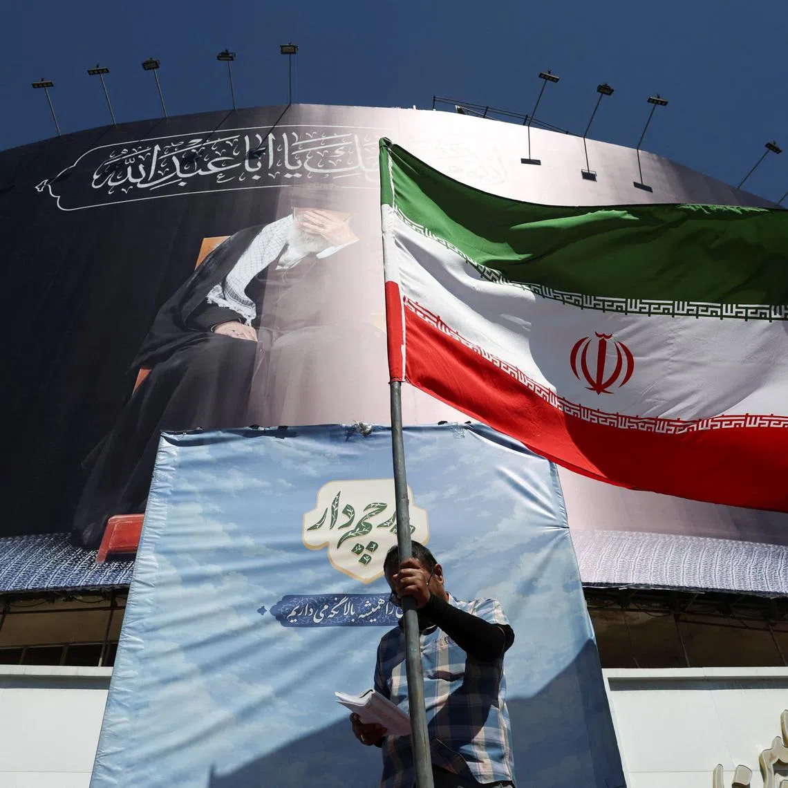 A man holds an Iranian flag on a street, after U.S. and Iranian officials said they had reached a deal to end their war and reopen the Strait of Hormuz, in Tehran, Iran, June 15, 2026. Majid Asgaripour/WANA (West Asia News Agency) via REUTERS