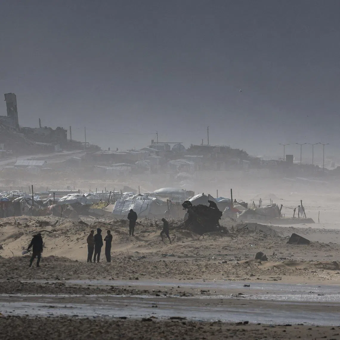 Palestinians gather near tents sheltering displaced people, amid a windstorm, in Gaza City, January 13, 2026. REUTERS/Dawoud Abu Alkas