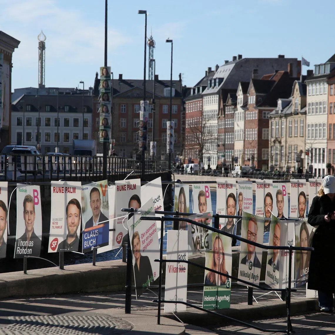 FILE PHOTO: A pedestrian stands next to posters for candidates in the upcoming Danish elections, in Copenhagen, Denmark, March 18, 2026. REUTERS/Tom Little/File Photo