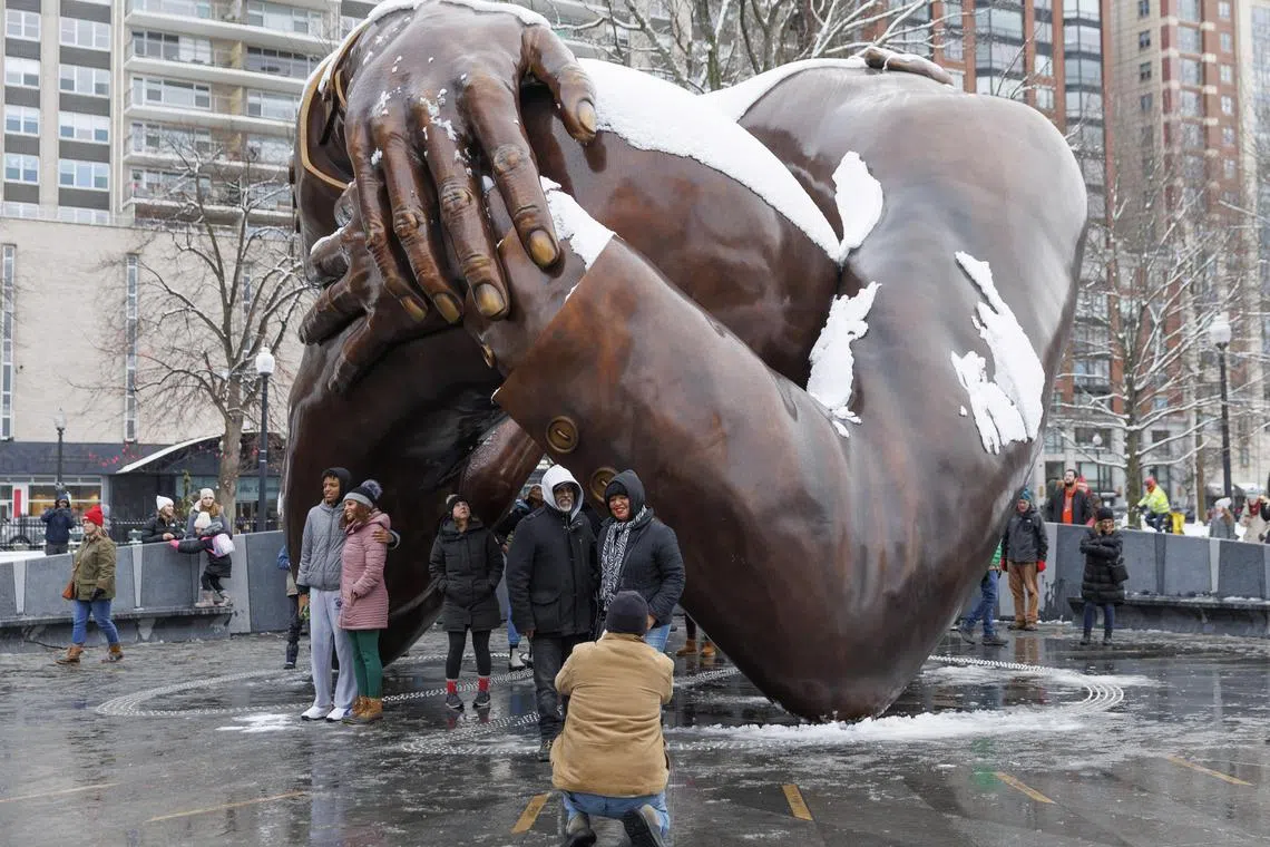 People pose at the Martin Luther King Jr. memorial statue, 'The Embrace,' on Martin Luther King Jr Day, on the Boston Common in Boston in Boston, Massachusetts, USA, 16 January 2023. The 22 foot (6.71 m) high bronze sculpture that sits on a circular granite plaza shows the intertwined arms of Martin Luther King Jr. and Coretta Scott King and was inspired by a photo of the couple smiling together moments after King won the Nobel Peace Prize in 1964.  
