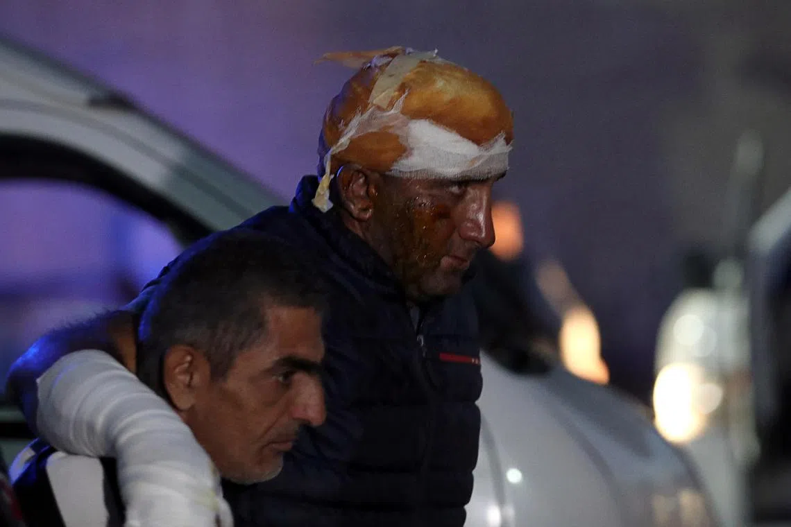 A man injured in the fuel depot blast is helped out of an ambulance at Armenia's National Burn Centre in Yerevan.