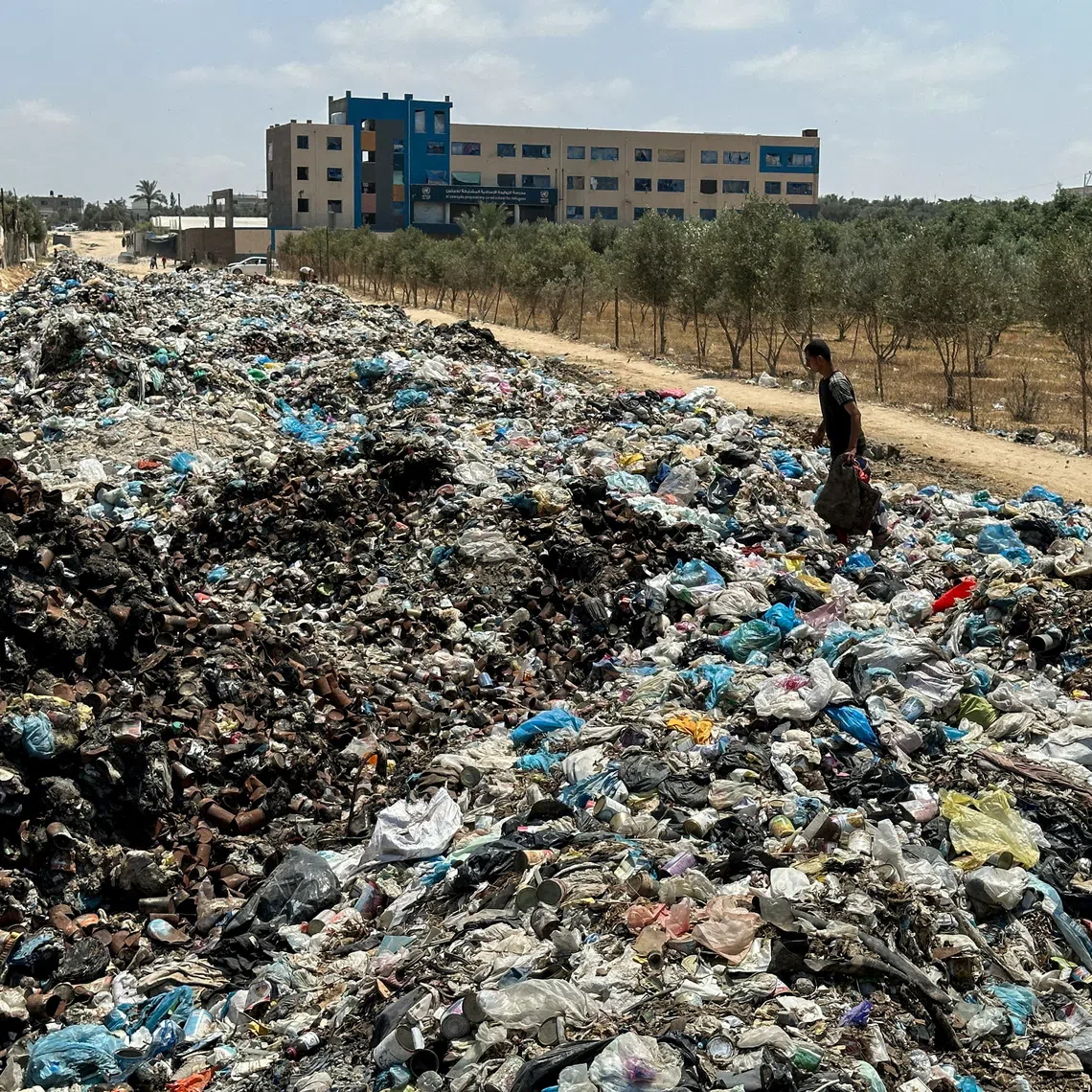 A Palestinian man walks on piles of garbage, amid the ongoing conflict in Gaza between Israel and Hamas, at Deir Al-Balah, in the central Gaza Strip, May 2, 2024. REUTERS/Doaa Rouqa