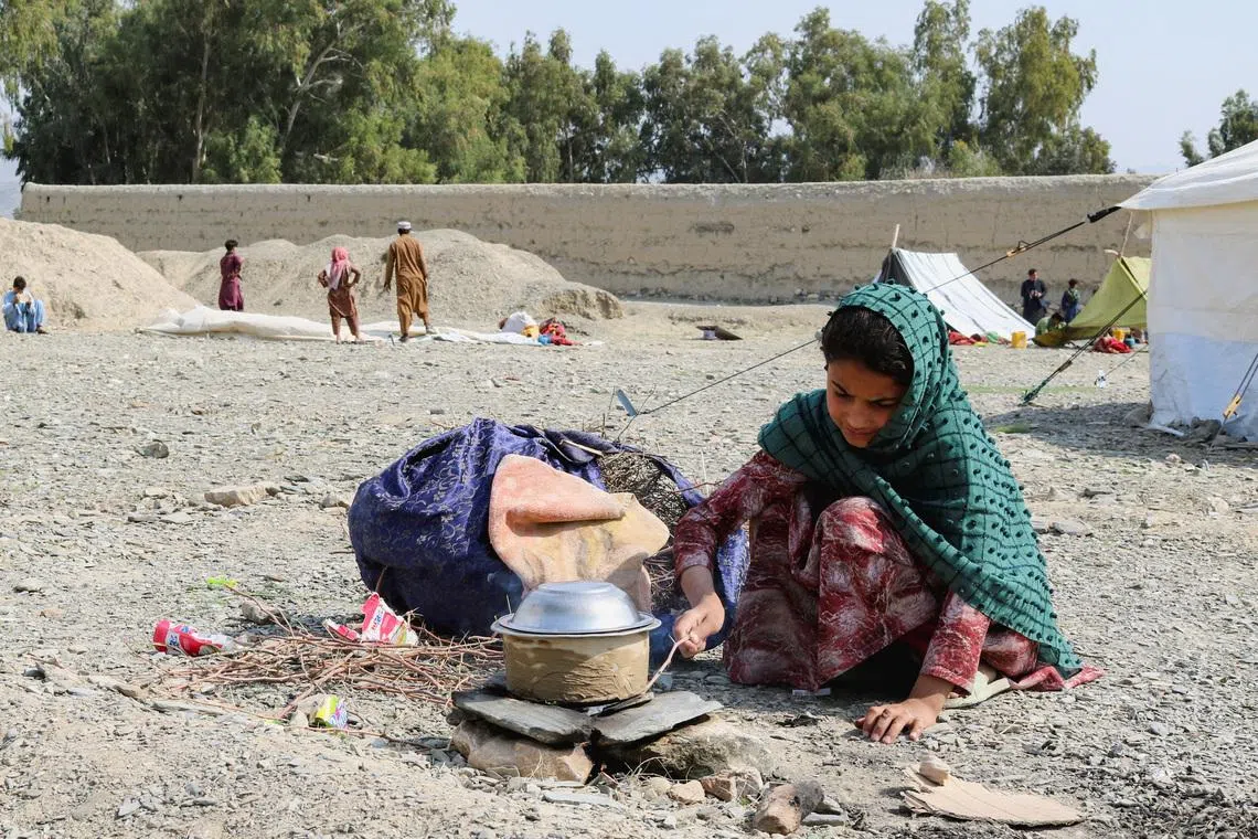 An Afghan girl cooks on a rock stove outside her family's tent as they take refuge in Lal Pur district in Afghanistan on March 4.
