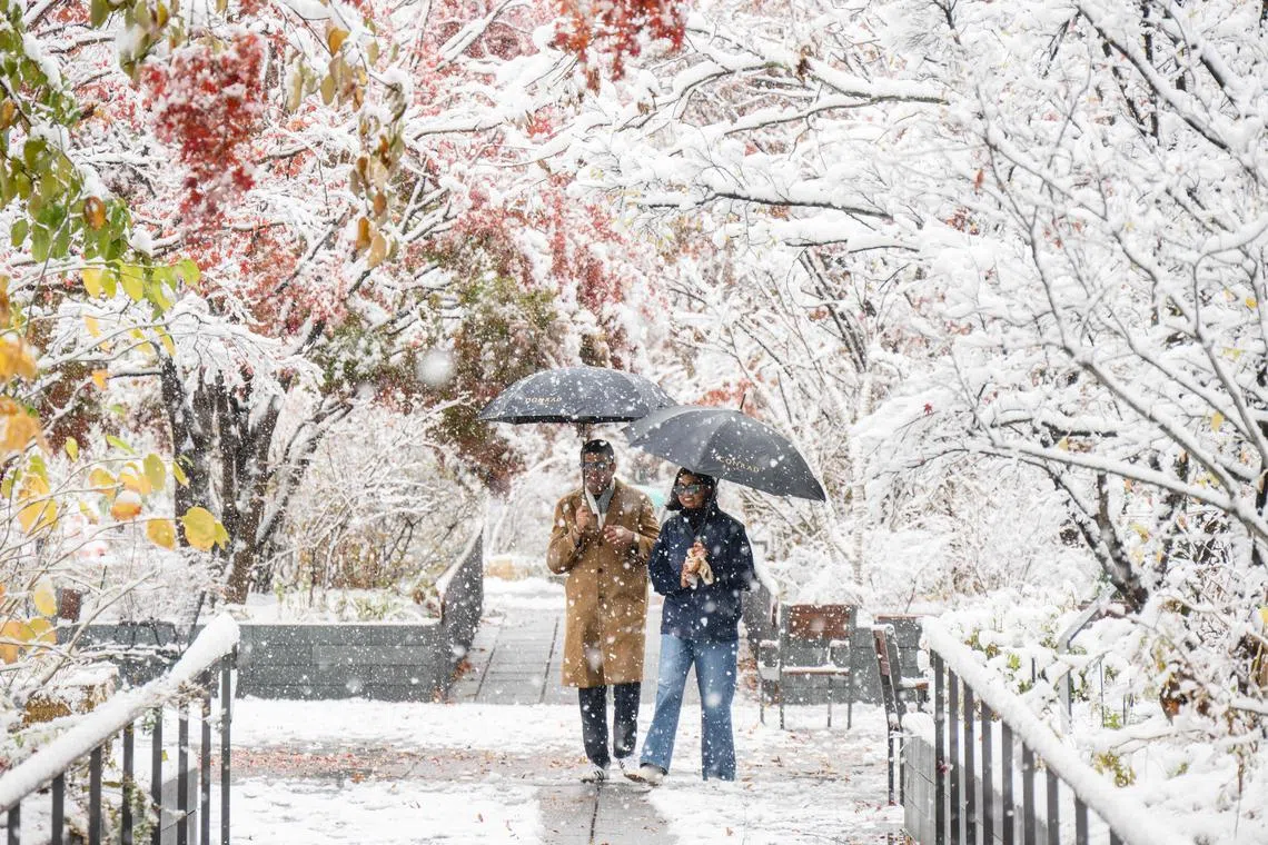 Pedestrians walking in Gwanghwamun near Gyeongbokgung Palace amid heavy snowfall in central Seoul on Nov 27, 2024. 
