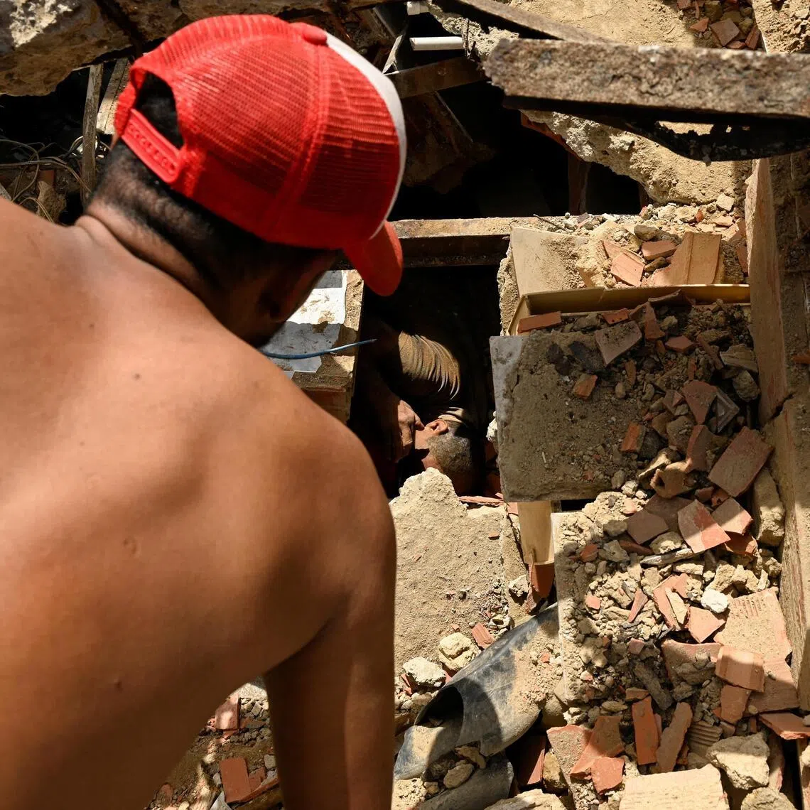 People work to rescue a man trapped under the rubble of a collapsed building, in the aftermath of earthquakes in La Guaira, Venezuela, June 25, 2026. REUTERS/Maxwell Briceno