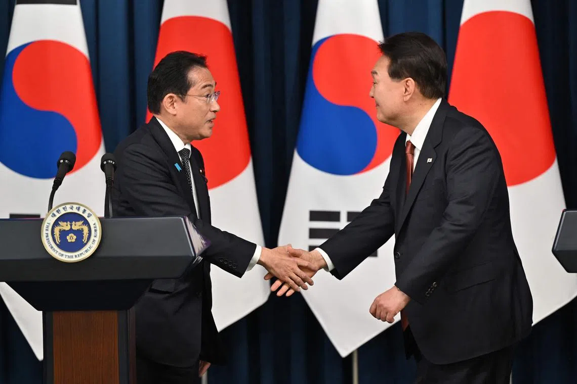 South Korean President Yoon Suk Yeol (R) shakes hands with Japanese Prime Minister Fumio Kishida (L) during a joint press conference after their meeting at the presidential office in Seoul on May 7, 2023. (Photo by JUNG YEON-JE / POOL / AFP)