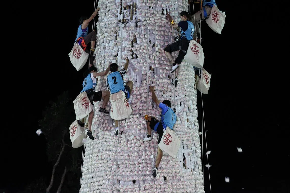 Participants competing to climb a 14-metre bun tower during the bun-snatching competition at the Cheung Chau Bun Festival in Hong Kong on May 25, 2026.