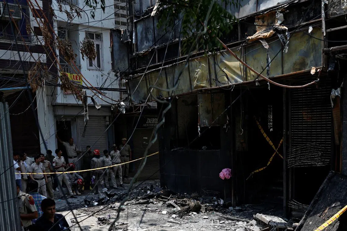 Firefighters and police officers work at the site after a fire at a hotel in New Delhi on June 3.