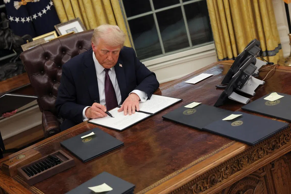 US President Donald Trump signing documents as he issues executive orders in the Oval Office at the White House on Inauguration Day in Washington on Jan 20. 