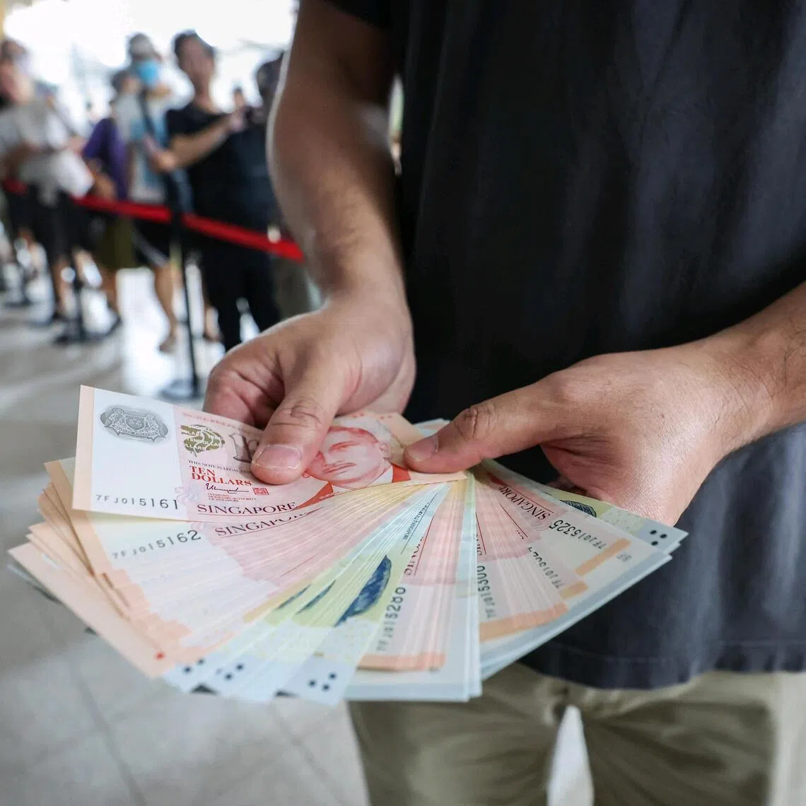 A customer showing the new notes he withdrew at a pop-up POSB ATM outside Clementi Community Centre on Jan 14, 2025. There were 101 people in the queues as of 11am. More than 125 machines began dispensing crisp banknotes – both new and used – to be stuffed in red packets for Chinese New Year (CNY), which begins on Jan 29.