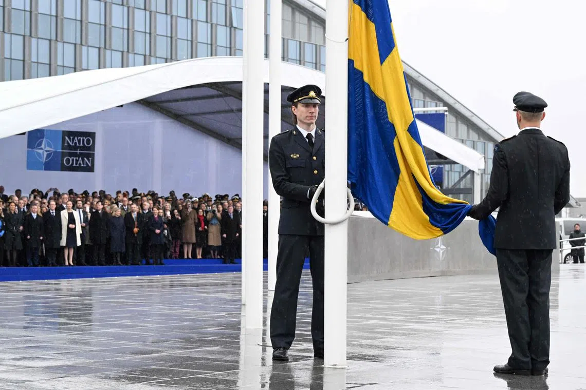 Officials hoist the Swedish national flag on a pole during a flag raising ceremony for Sweden's accession to NATO on March 11, 2024. 