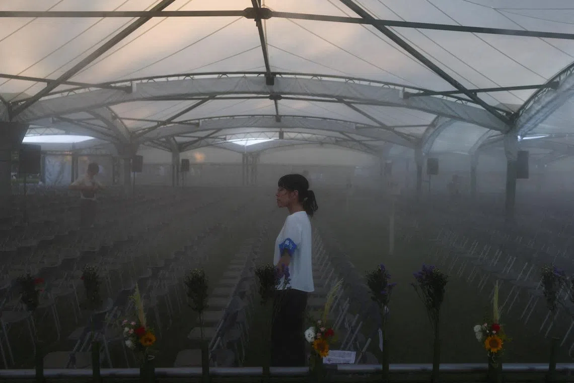 A staff member waits for the arrival of attendees as water mist sprinklers are used to cool the venue for an event marking the 80th anniversary of the atomic bombing in Hiroshima, western Japan, August 6, 2025. REUTERS/Kim Kyung-Hoon     TPX IMAGES OF THE DAY