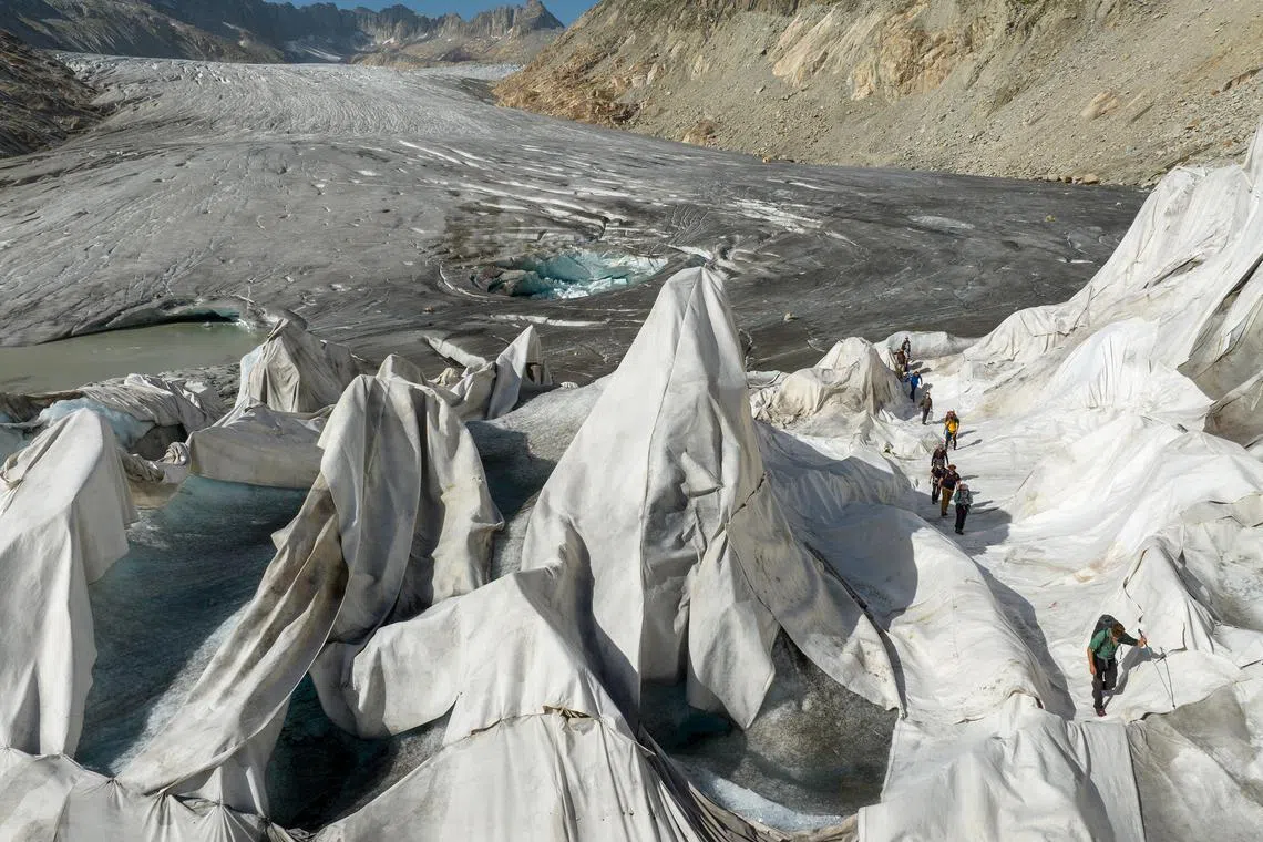 A team from ETH Zurich, a research university, walking through a part of the Rhône Glacier draped in tarps to slow down the melting, Aug 23, 2023. 