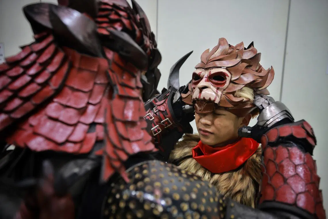 Firmanda Romas, 39, helps his son Firgian Arfa Imanda Romas, 15, with his helmet, after the latter won the cosplay competition during Singapore Comic Con in a costume of Wukong from video game League of Legends. The older Mr Romas, dressed as Rathalos Armor from Monster Hunter, was also a finalist.