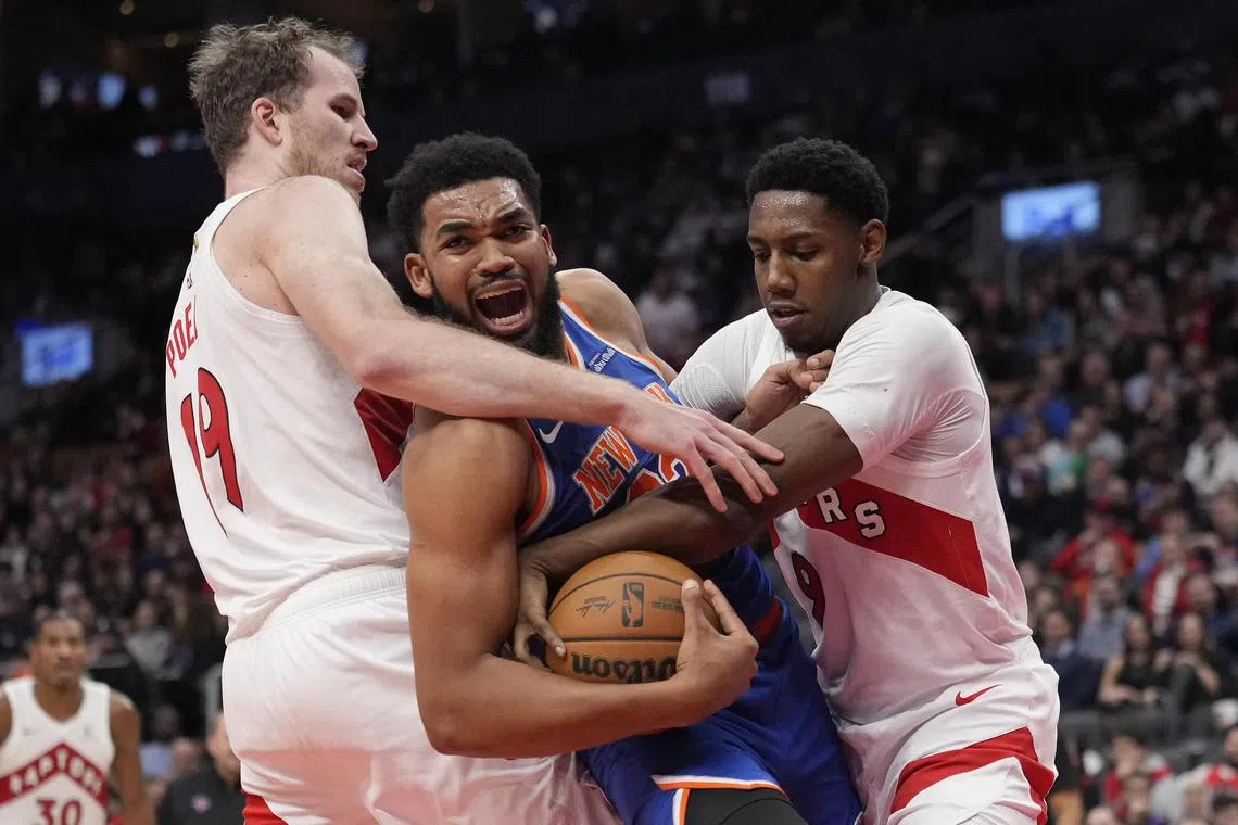 New York Knicks centre Karl-Anthony Towns fights for the ball with Toronto Raptors centre Jakob Poeltl and guard RJ Barrett during the second half at Scotiabank Arena.