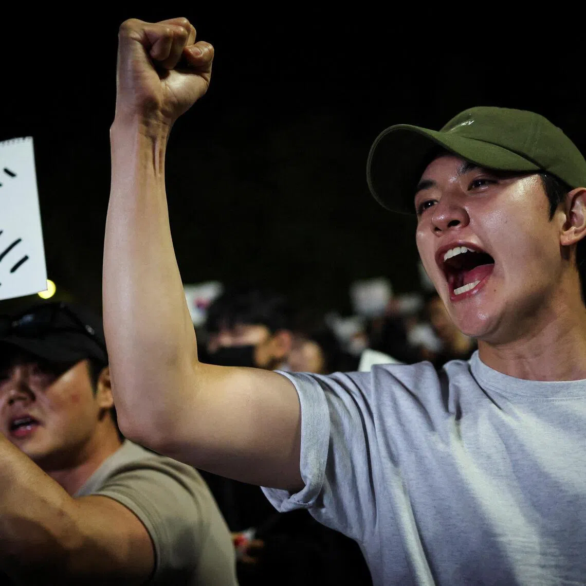A demonstrator raises his fist as people surround a vote-counting centre to protest a controversy over a shortage of ballot papers.
