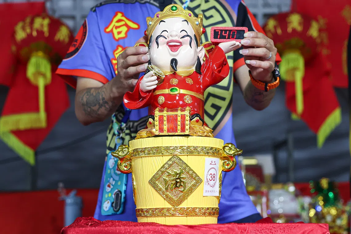 Close-up of an ornamental God of Fortune statue atop a bucket being auctioned during a Hungry Ghost Festival dinner auction in Toa Payoh on Aug 23, 2026. ST PHOTO: BRIAN TEO
