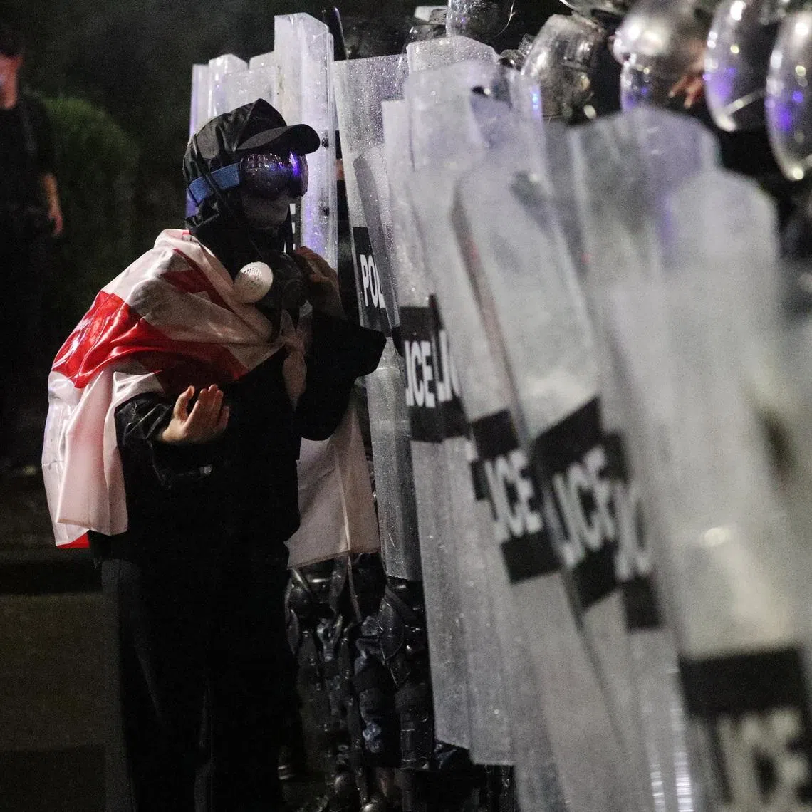 A protester wearing a Georgian flag talks to police officers blocking the street during an opposition rally on the day of local elections in Tbilisi, Georgia October 4, 2025. REUTERS/Irakli Gedenidze