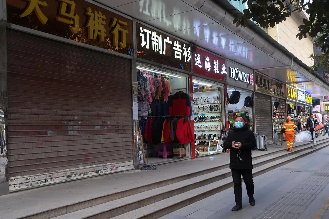 A person walks past a shop closed for business, after the government eased curbs on the coronavirus disease (COVID-19) control, in Wuhan, Hubei province, China December 10, 2022. REUTERS/Martin Pollard