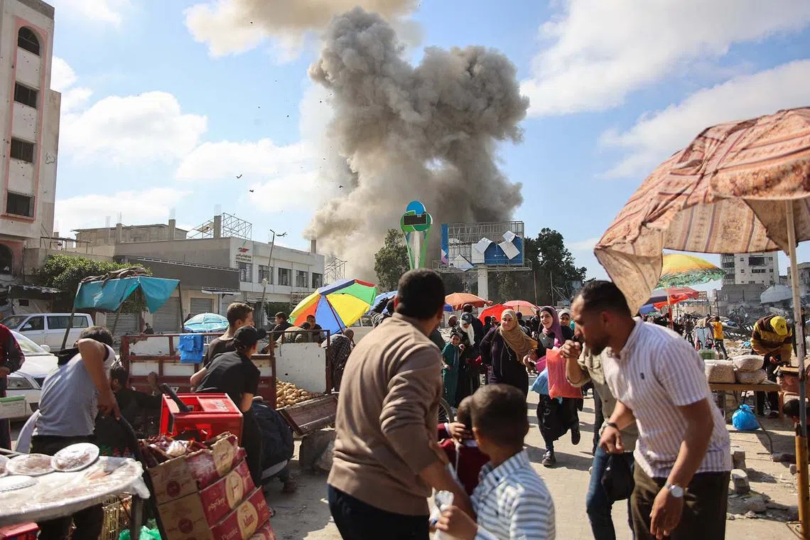 Palestinians looking at billowing smoke during Israeli's bombardment of the Firas market area in Gaza City on April 11, 2024.