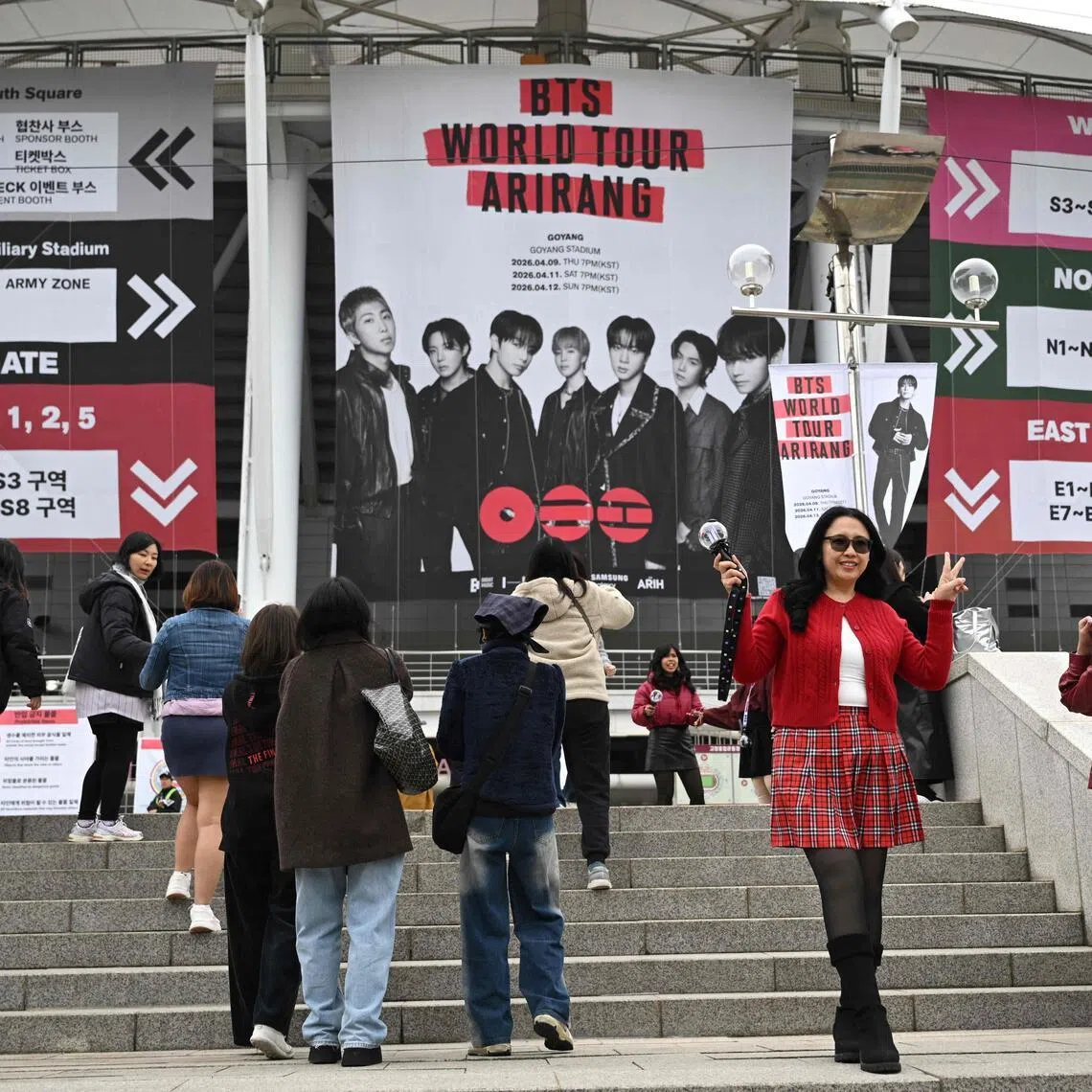 Fans pose in front of a large banner featuring BTS at the stadium where the group will perform in Goyang on April 9, 2026. 