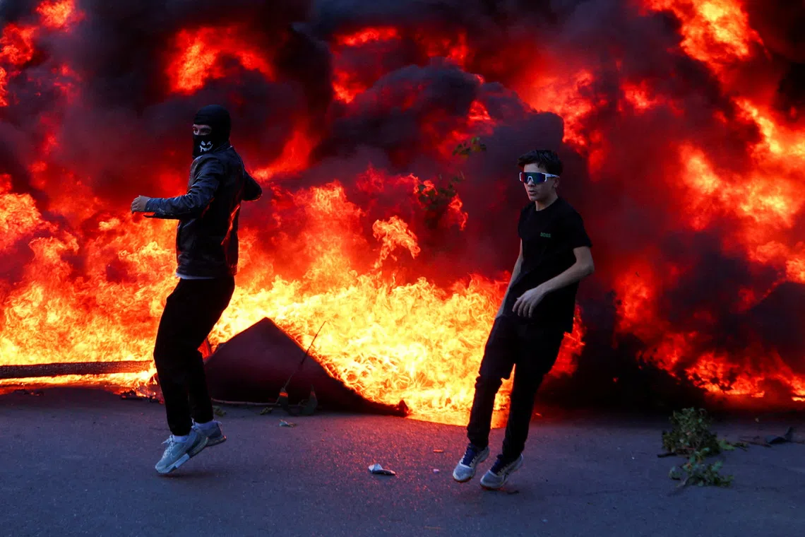 People react near a burning fire, as plumes of black smoke rise, amid an anti-government protest by students, in Tirana, Albania, October 14, 2026. REUTERS/Florion Goga