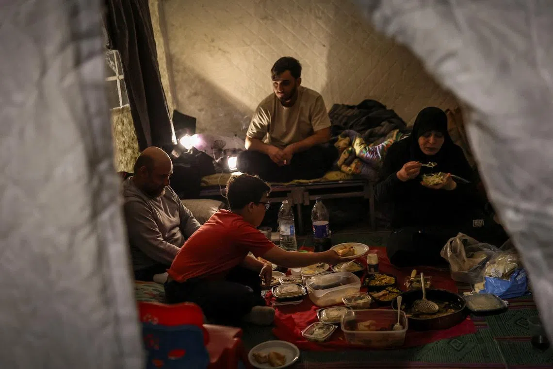 Salam Issa Rida, 43, her husband Ahmed Rida, 43, and other family members break their fast at iftar during Ramadan as they shelter at Camille Chamoun Stadium, following an escalation between Hezbollah and Israel amid the U.S.-Israeli conflict with Iran, in Beirut, Lebanon, March 14, 2026. REUTERS/Claudia Greco