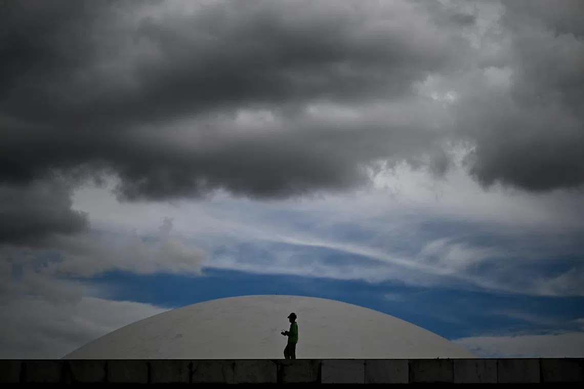 A man walking past the National Congress marquee, in front of the Federal Senate dome, in Brasilia, Brazil, on March 26, 2025.  