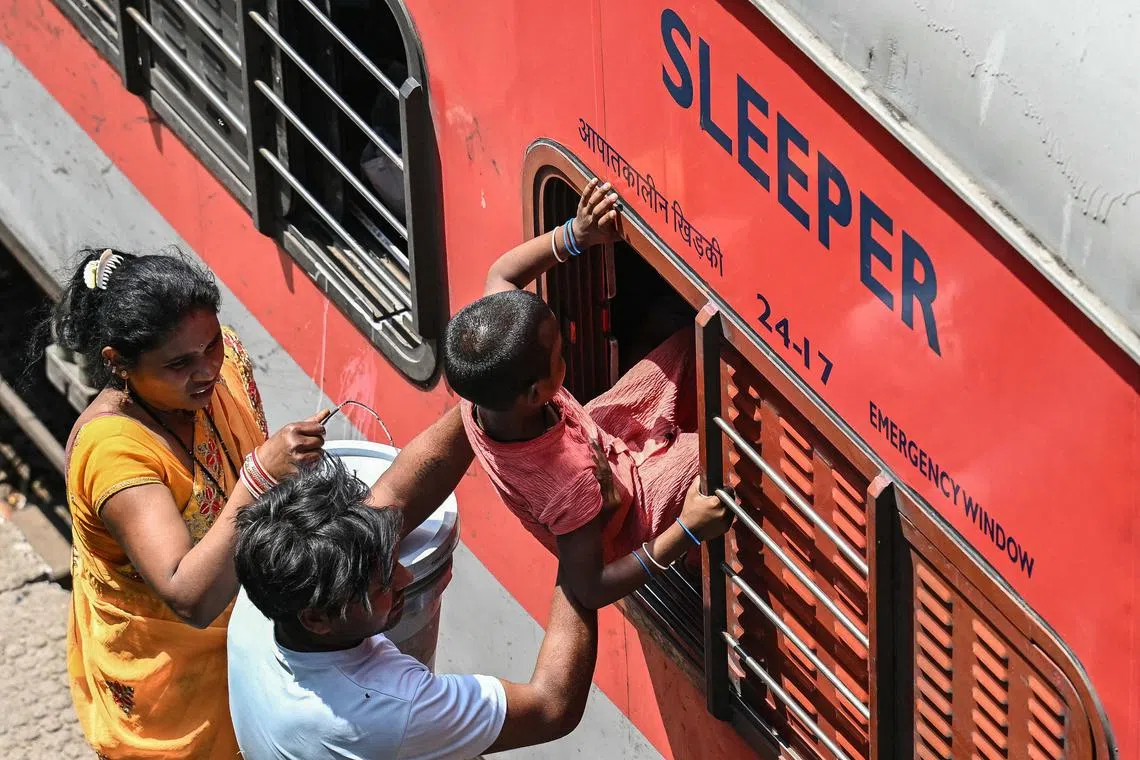 A man helps his child to board an overcrowded train at the Jammu Tawi railway station on May 10.