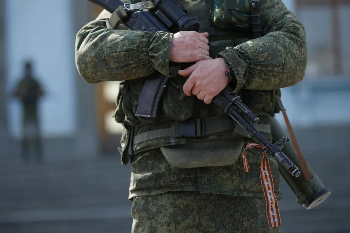 An armed man with a St George's ribbon on his weapon stands guard in the city of Simferopol, on the Russian-occupied Ukrainian peninsula of Crimea.