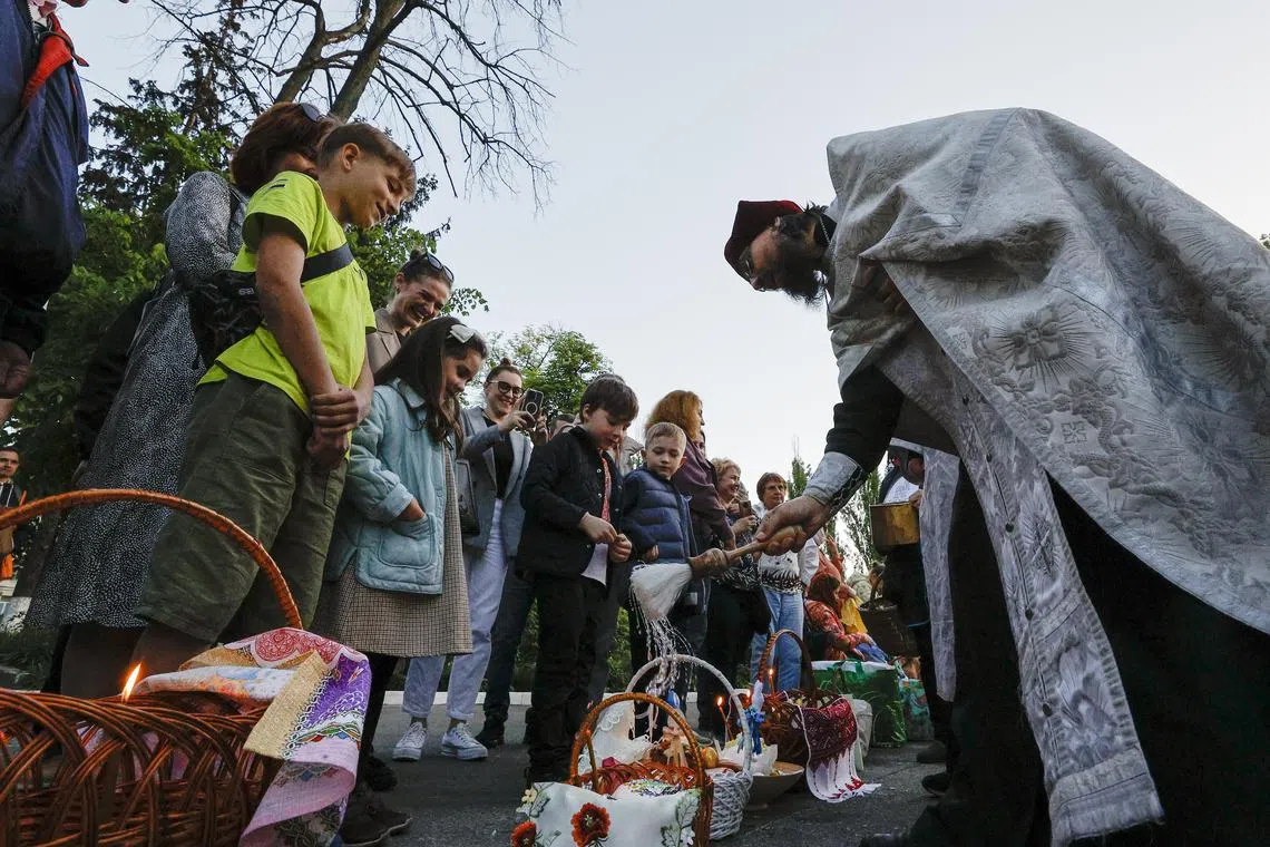 A Ukrainian priest blesses believers and their baskets containing painted eggs and kulichi, a traditional Easter cake, ahead of an Orthodox Easter mass at St. Volodymyr Cathedral in Kyiv, Ukraine.
