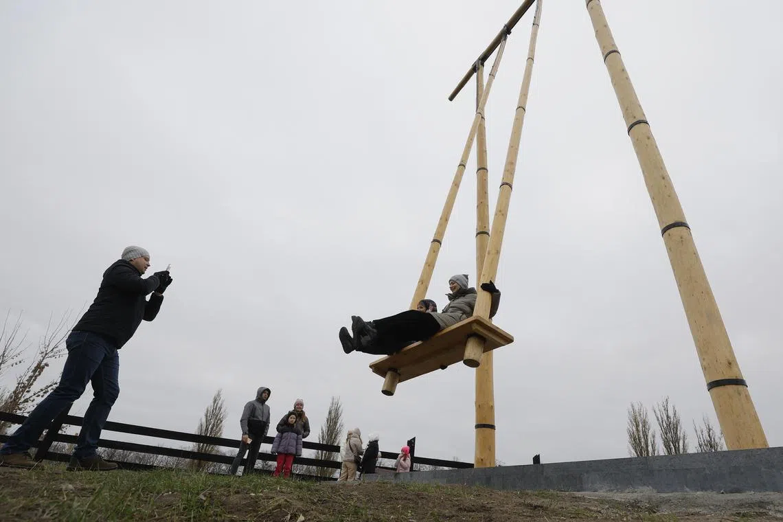 People sitting on a giant swing in Ukraine on Nov 19, 2023, amid the ongoing Russian invasion. The swing, made from solid wooden logs and standing at a height of 12.3 meters, has a foundation that is 3.5 meters deep. Capable of accommodating two or three people simultaneously, it has been registered in the National Register of Records of Ukraine as the highest swing in the country