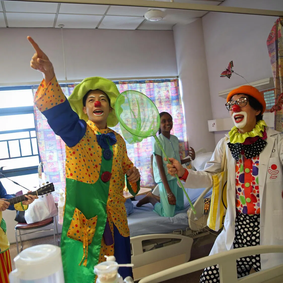 11-year-old Vinitha Suresh (second from right) reacts as members of the Caring Clown Unit (from left) Shootie, Rong Er and Rojo, comically search for butterflies in the ward. It is part of Rojo's signature act to engage his audience - he endlessly hunts for butterflies that he cannot see on top of his hat. Formed in 2004, the Caring Clown Unit (CCU) Singapore is a not-for-profit outfit, that started with the expressed objective of making a positive difference in the lives of hospitalised patients, their families and caregivers by spreading warmth and cheer through humorous ward entertainment. The volunteers visit the paediatric wards of KK Women’s and Children’s Hospital every last Saturday of the month to sculpt balloons, perform magic tricks, and basically be silly, to try and make a child smile.