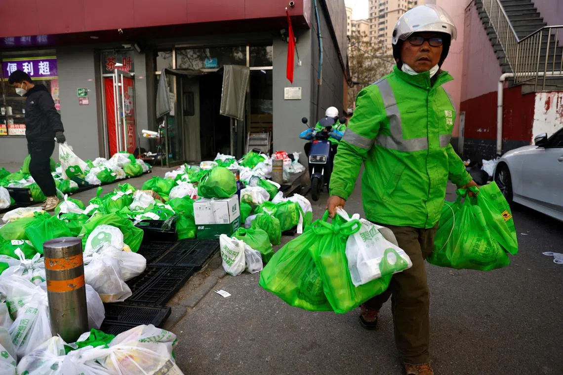 A delivery worker picks up goods at a logistics station of online grocery platform by Meituan, following a Covid-19 outbreak in Beijing.