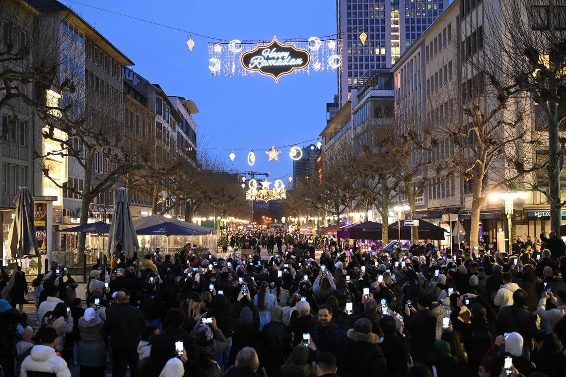 People take pictures of a street in Frankfurt illuminated during the month of Ramadan. 