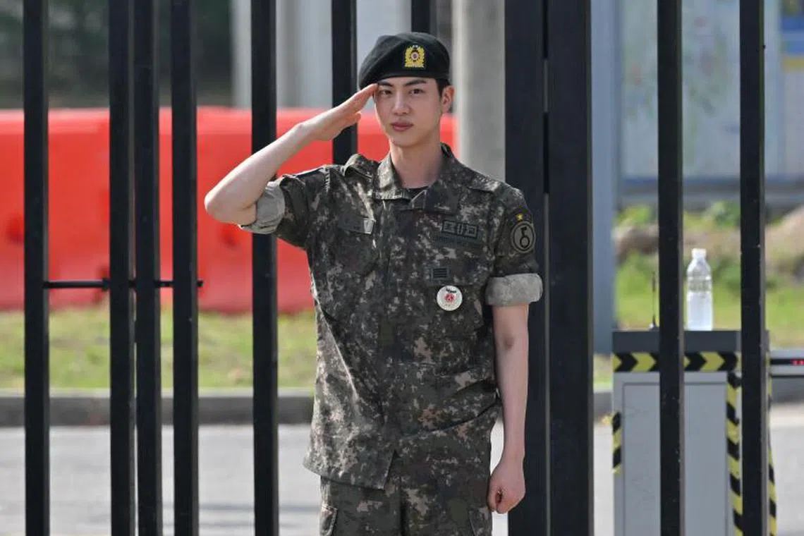  K-pop boy band BTS member Jin salutes after being discharged from his mandatory military service in front of a military base in Yeoncheon on June 12, 2024.  Jin will be one of the torchbearers for the Paris Olympic flame.