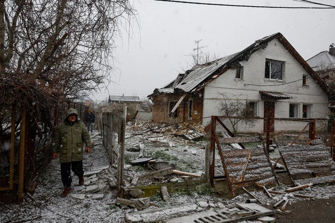 Residents walk next to a house in a residential area damaged during a Russian drone strike, amid Russia's attack on Ukraine, in Kyiv, Ukraine April 10, 2025. REUTERS/Valentyn Ogirenko