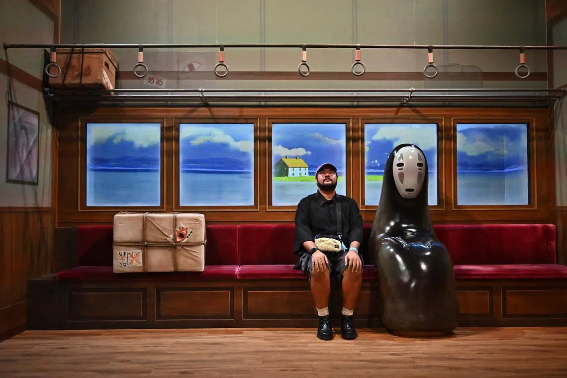A man sits next to the character No Face from the Studio Ghibli movie Spirited Away.