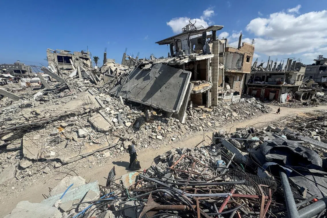 FILE PHOTO: Palestinians walk near rubble and destroyed buildings, amid the Israel-Hamas conflict, in Khan Younis, in the southern Gaza Strip, October 10, 2024. REUTERS/Mohammed Salem/File Photo