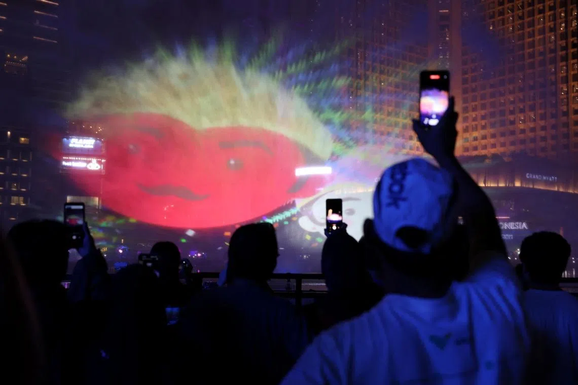 People use their mobile phones as they watch a video mapping show at the Bundaran Hotel Indonesia roundabout while celebrating New Year's Eve in Jakarta, Indonesia, December 31, 2023. REUTERS/Ajeng Dinar Ulfiana