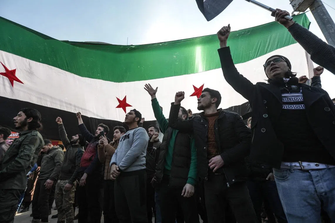 Demonstrators raise Syrian opposition flags and placards as they rally against a potential rapprochement between Ankara and the Syrian regime, on Dec 30, 2022, in the opposition-held city of Al-Bab, on the border with Turkey, in Syria's northern Aleppo province.