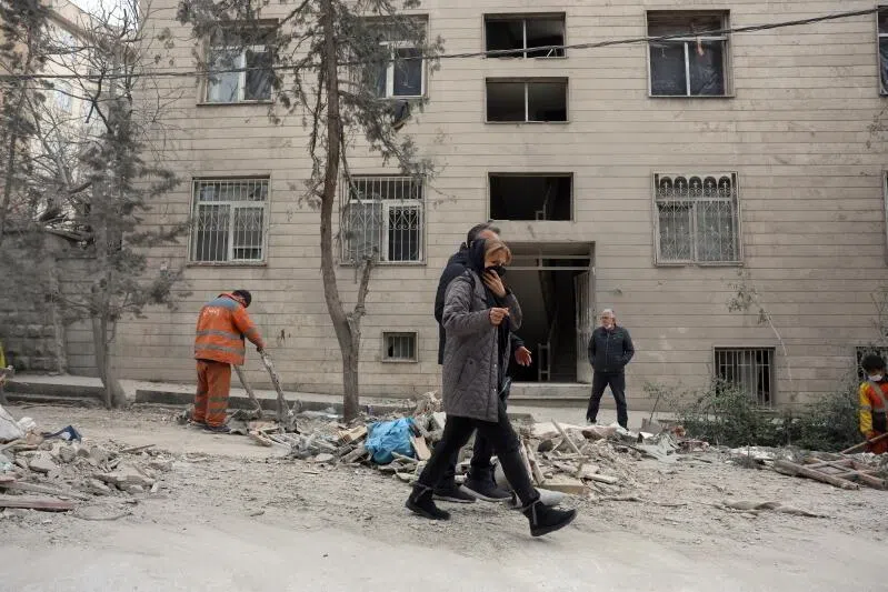 Locals walk past a damaged residence after an airstrike in northern Tehran, Iran, on March 29.