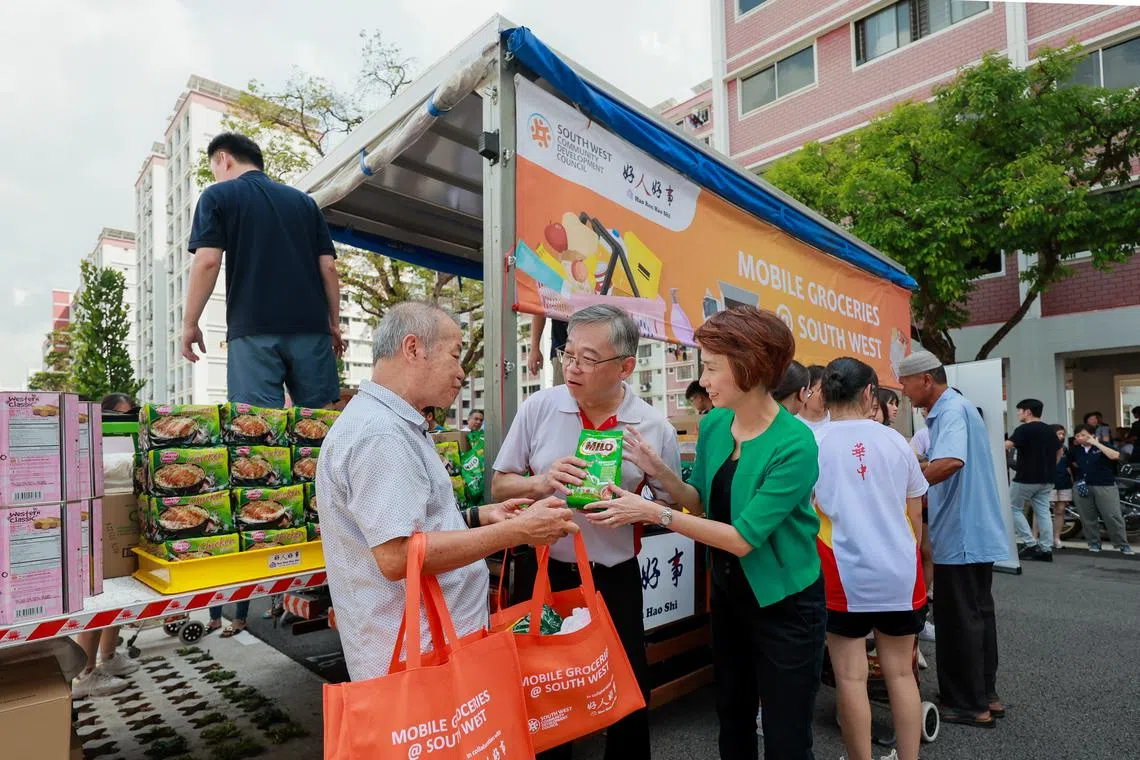 Trade and Industry Minister Gan Kim Yong (centre) and South West District mayor Low Yen Ling (right) handing groceries to a resident on April 27.