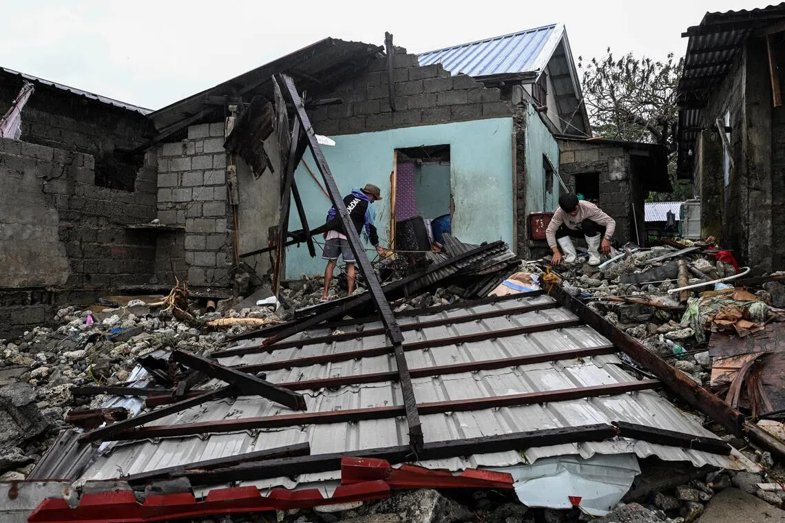 Men look for belongings in front of their house damaged by storm surges after Typhoon Fung-wong hit the coast of Alacan, Pangasinan, Philippines, on Nov 11.