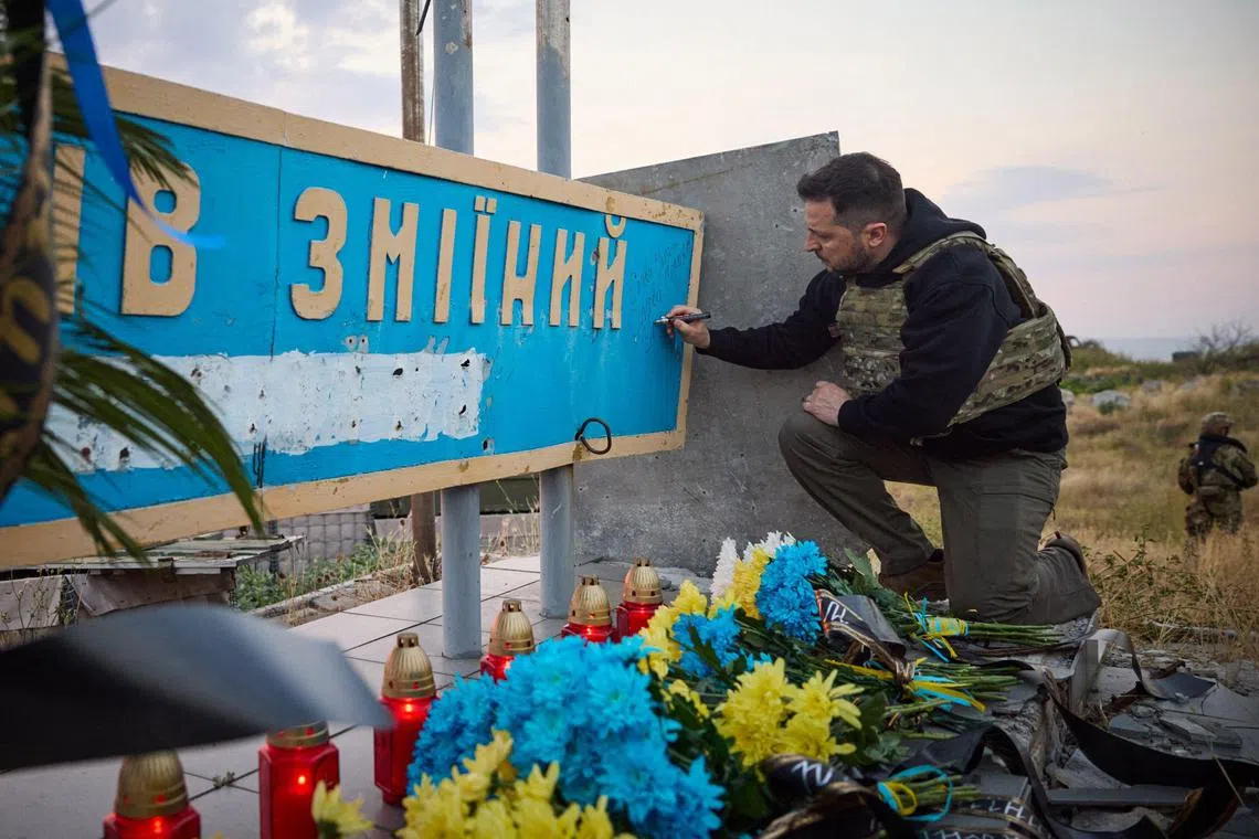 Ukraine's President Volodymyr Zelensky leaves a message on a sign reading "Snake Island" during his visit to the Snake Island.