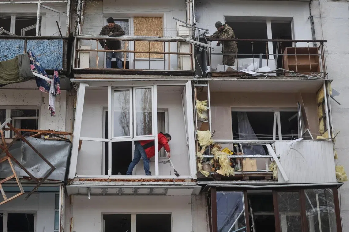 People are seen in a residential building damaged by a Russian missile strike, near the town of Chuhuiv, in Ukraine's Kharkiv region.