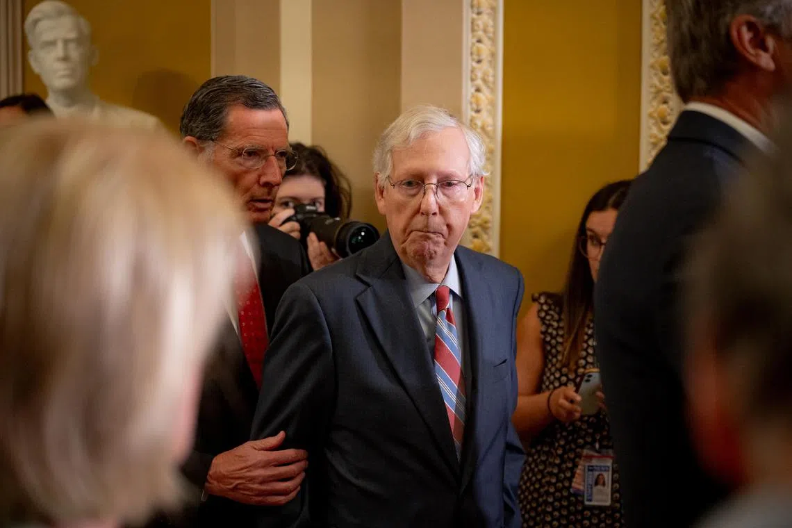 Colleagues and aides help Senate Minority Leader Mitch McConnell walk way from the microphones after freezing during a weekly news conference.