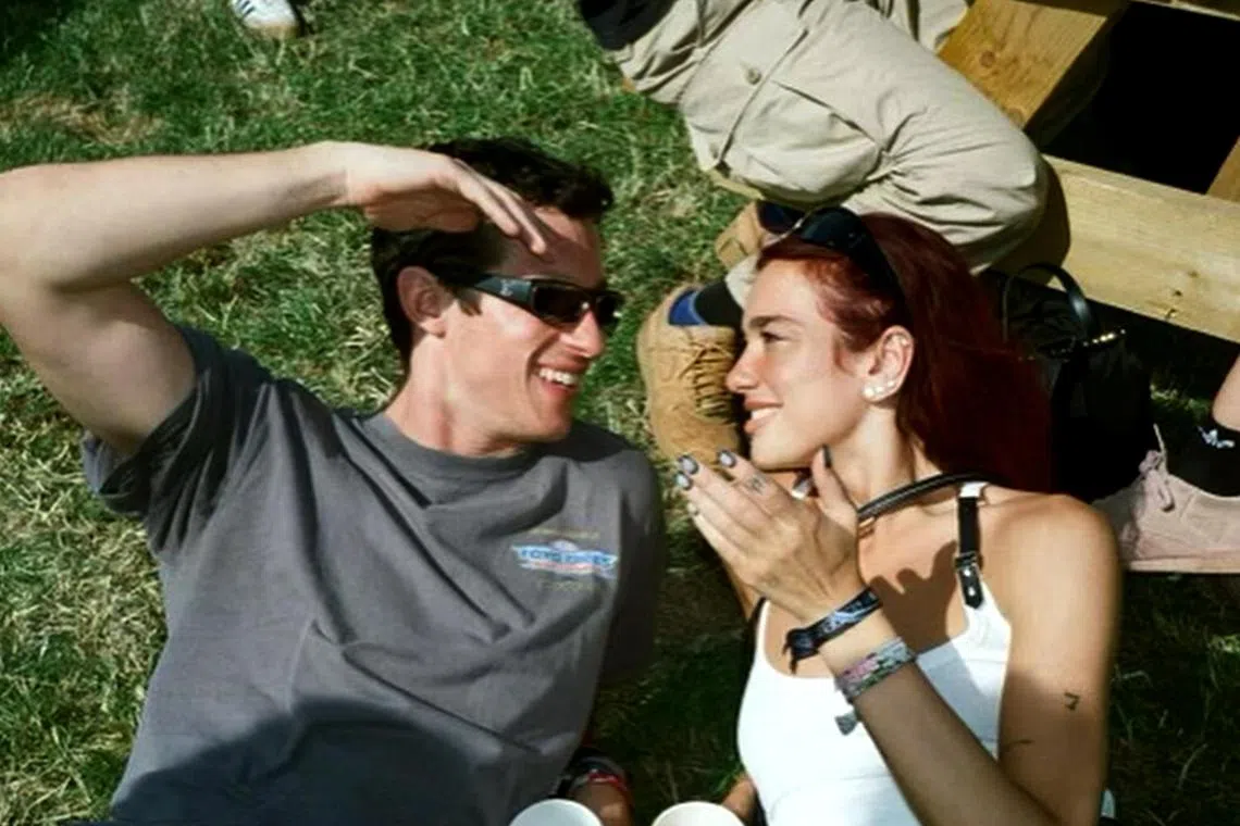 In a photo, Dua Lipa (right) and Callum Turner were shown lying on the grass looking at each other, while holding two drinks.  
