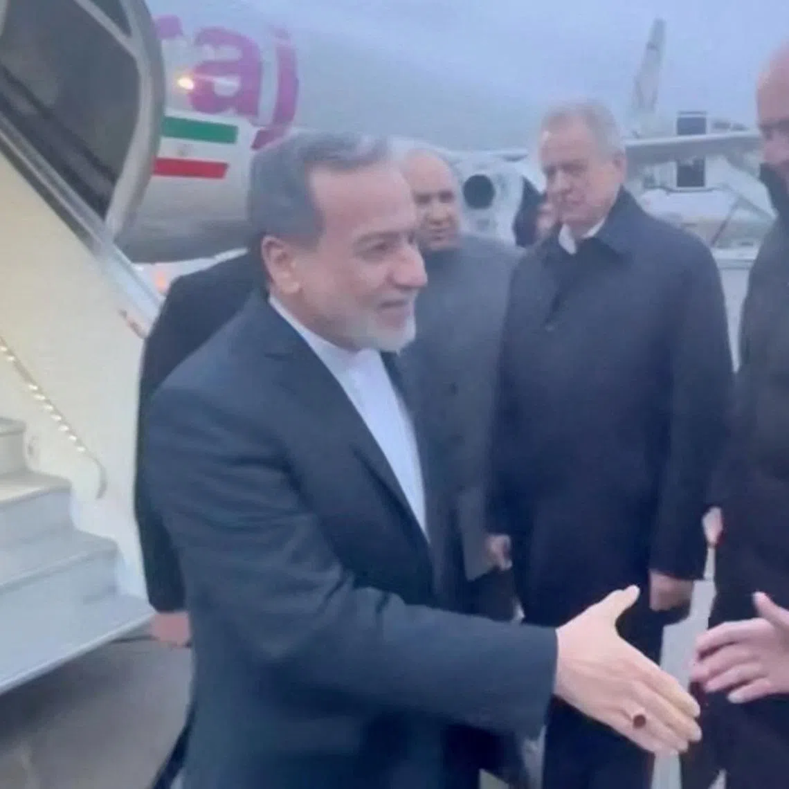 Iran's Foreign Affairs Minister Abbas Araqchi (left) is greeted by officials during his visit to Russia for talks with Russian President Vladimir Putin, in a place given as St. Petersburg on April 27.